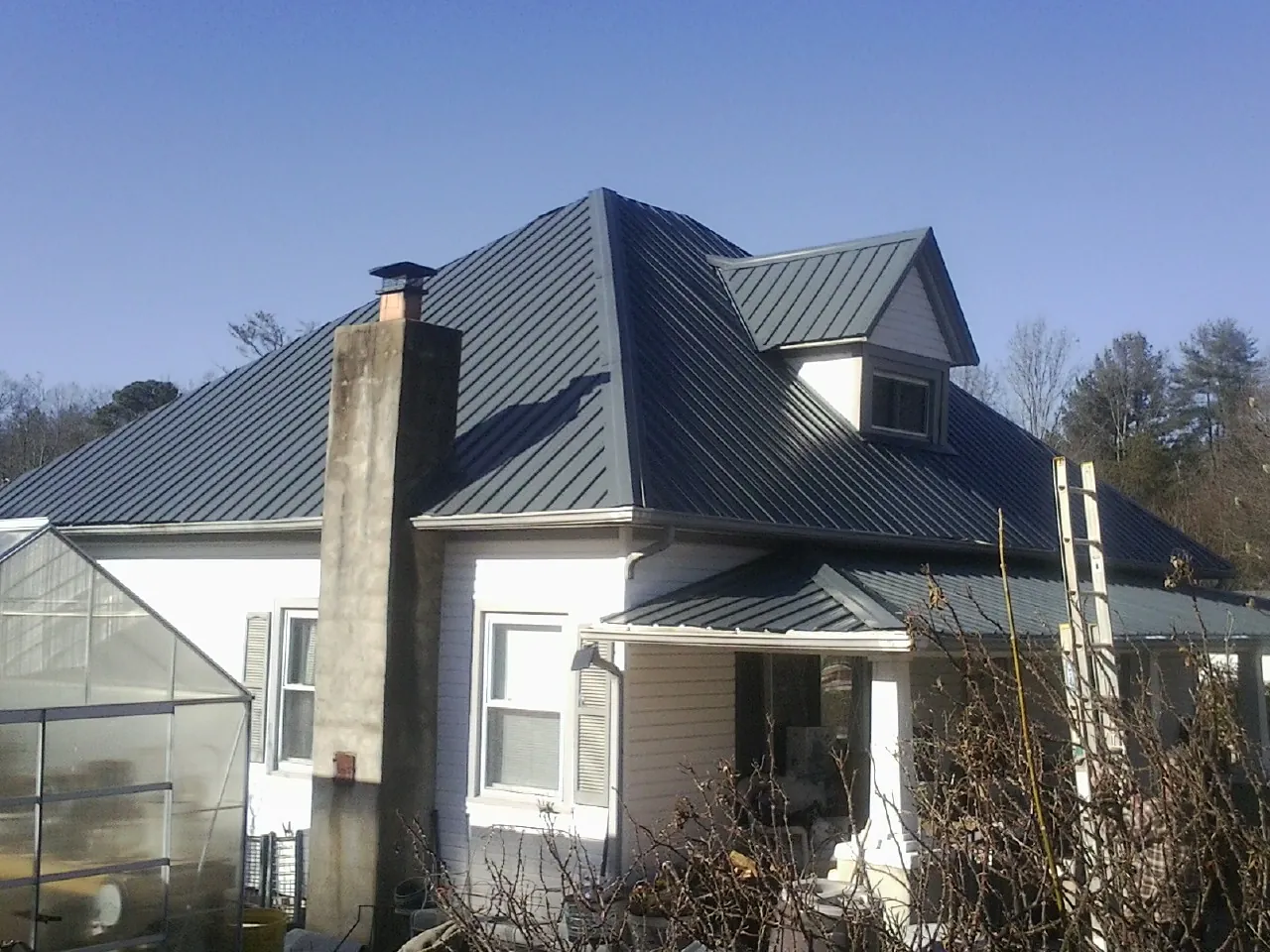 Dark blue standing seam metal roof on a white farmhouse with dormer — Slate & Tile Roof Repair by Roofing Brothers in Duncan