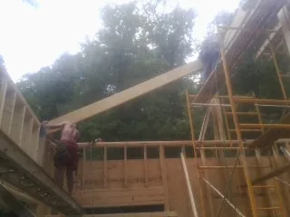 Carpenter raising a rafter beam on a new second story frame in Duncan