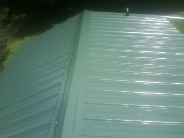 New green metal panels meeting at the ridge of a roof — Flat Roof Repair work by our crew in Duncan
